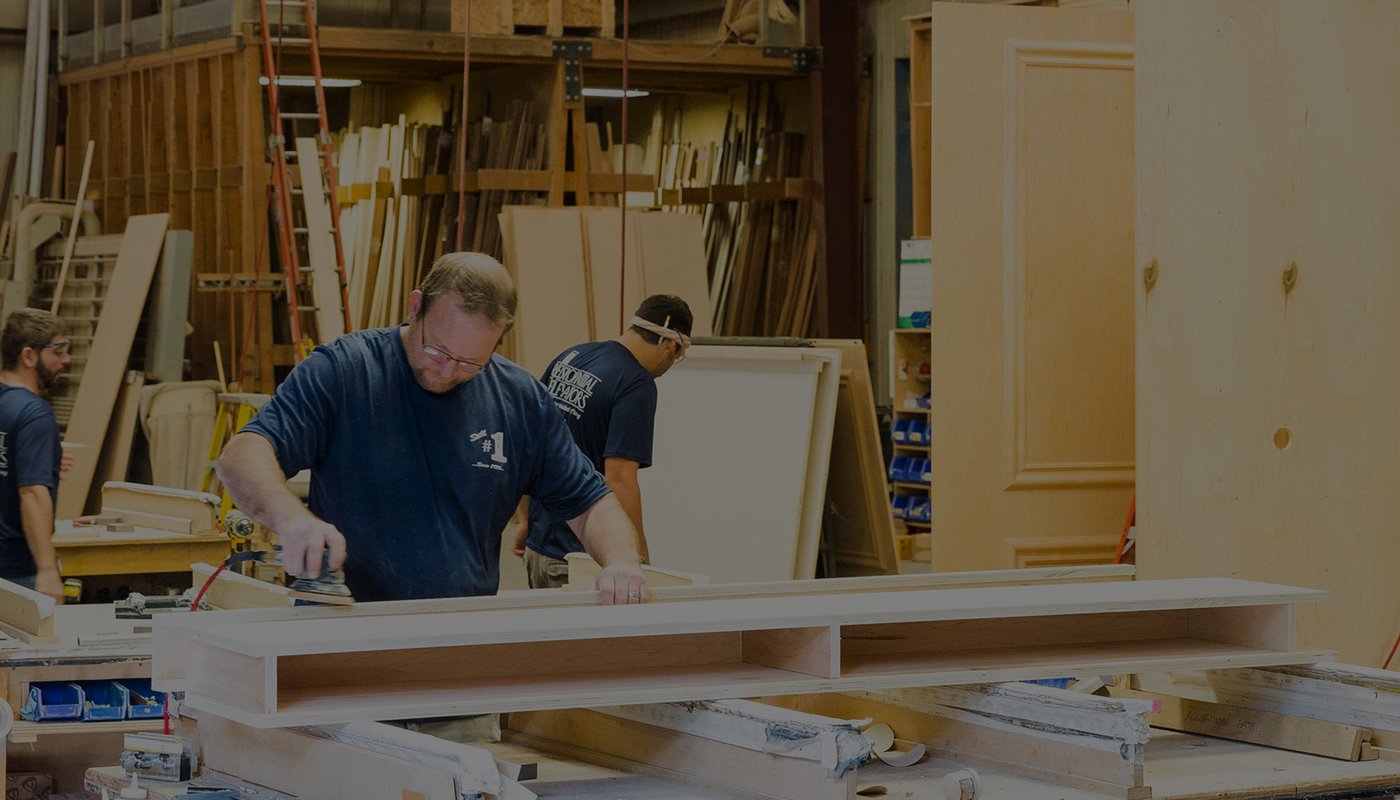 Workers sanding and assembling wood pieces in a carpentry workshop