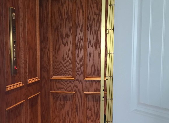 Elevator interior with beautiful wood paneling and gold gate