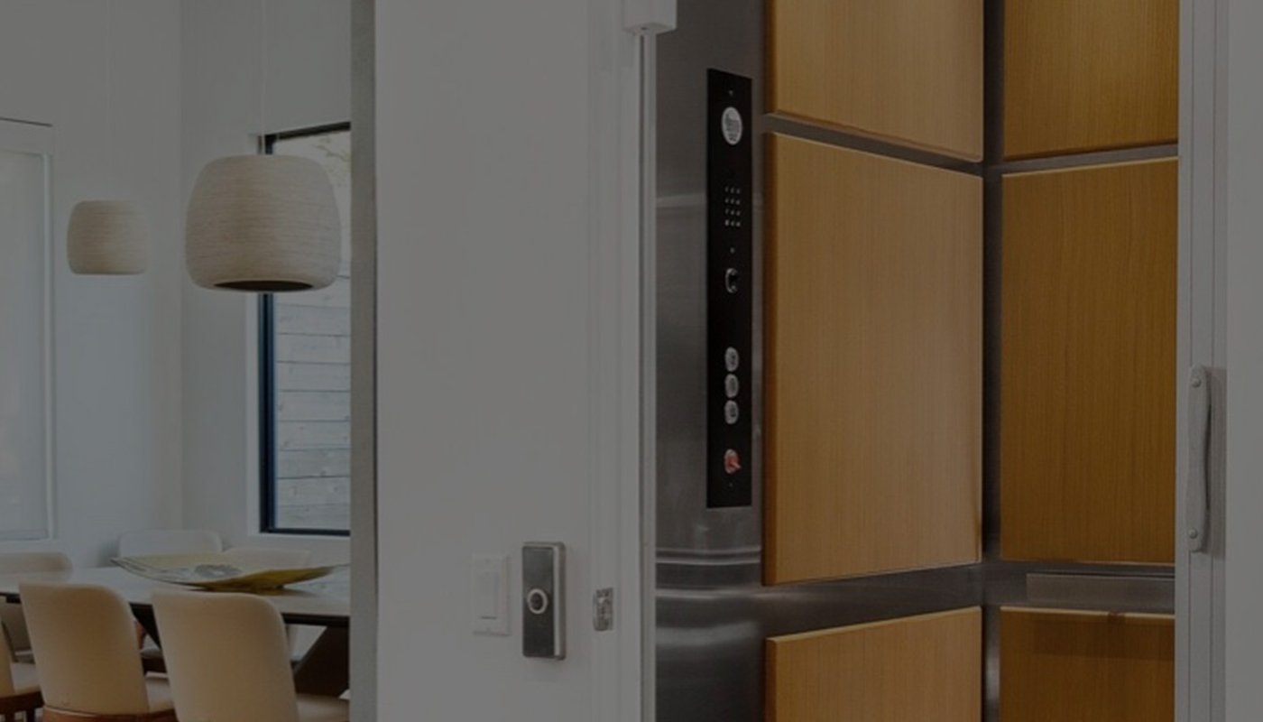 Elevator with light wood paneling next to modern dining room