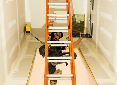 worker installing home elevator in shaft