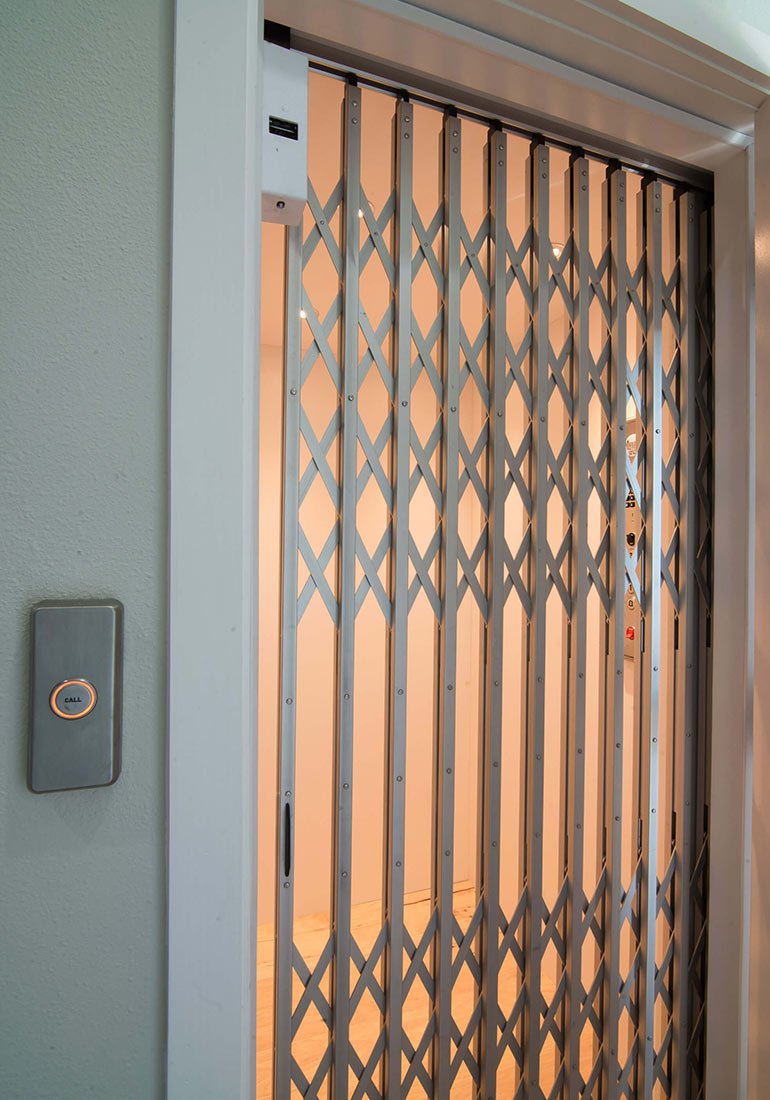 Home elevator with gate closed and call button on wall