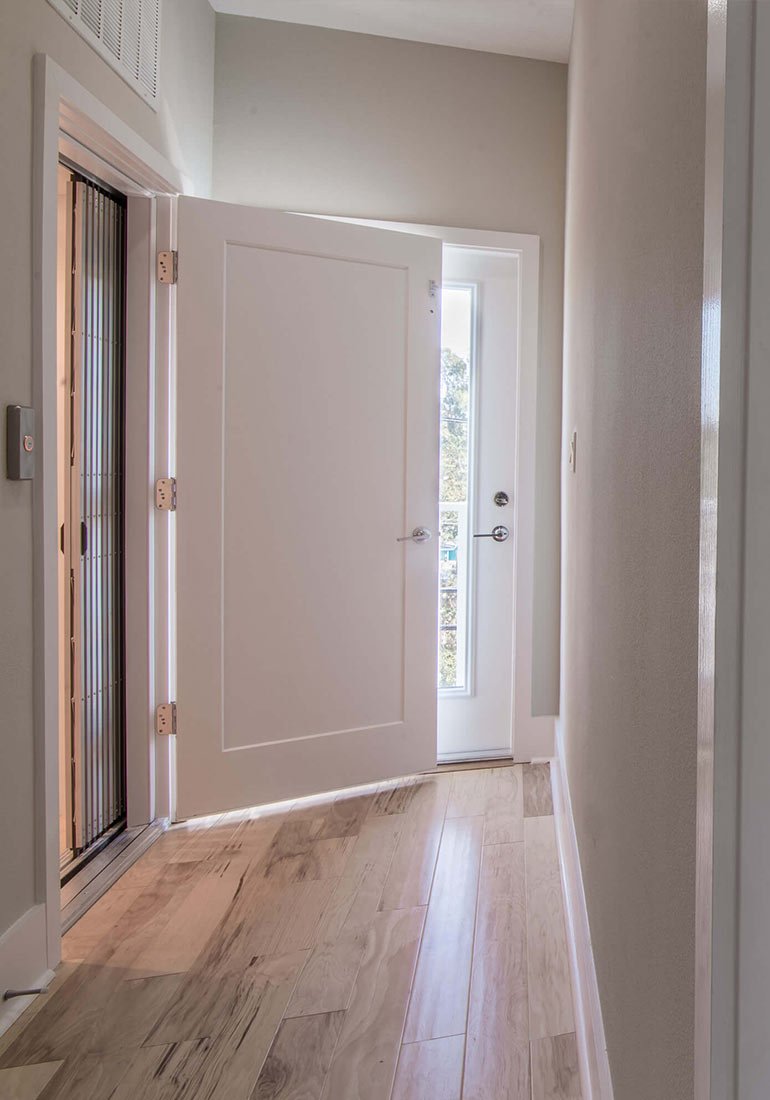 Hallway with an open elevator door beside a white entry door