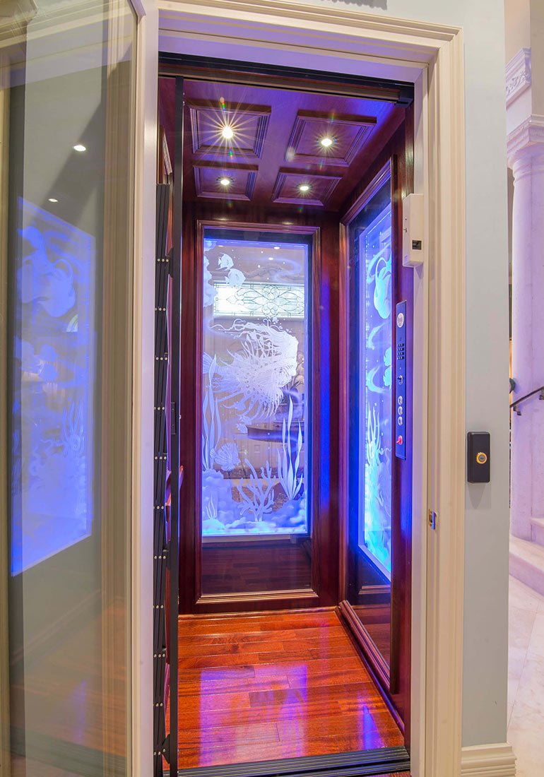 Ornate home elevator with glowing ocean-themed glass panels and wood interior