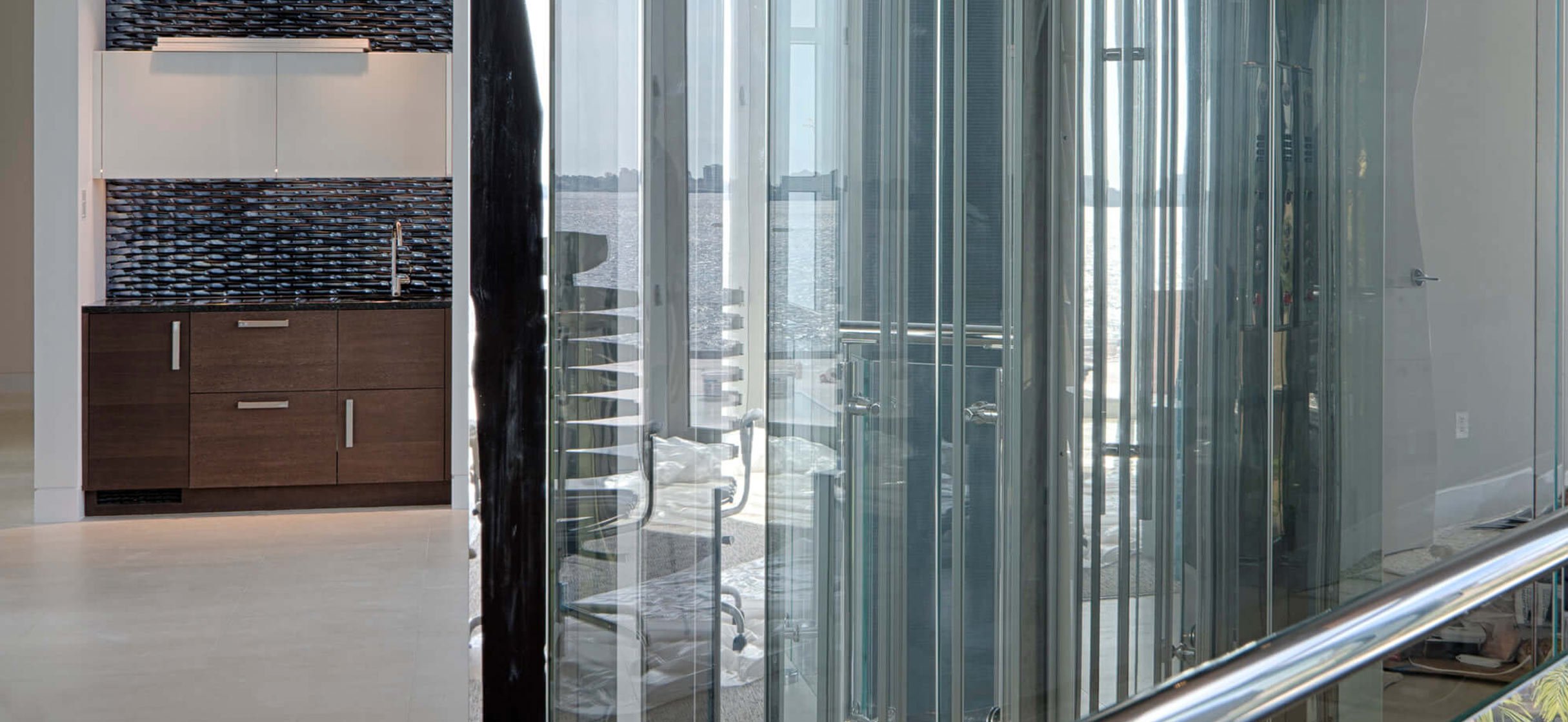 Glass-walled home elevator next to a modern kitchen area