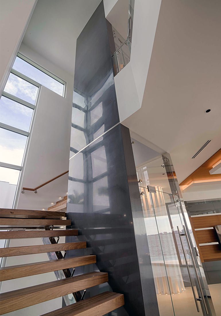 Modern home interior with wooden stairs beside a tall elevator shaft
