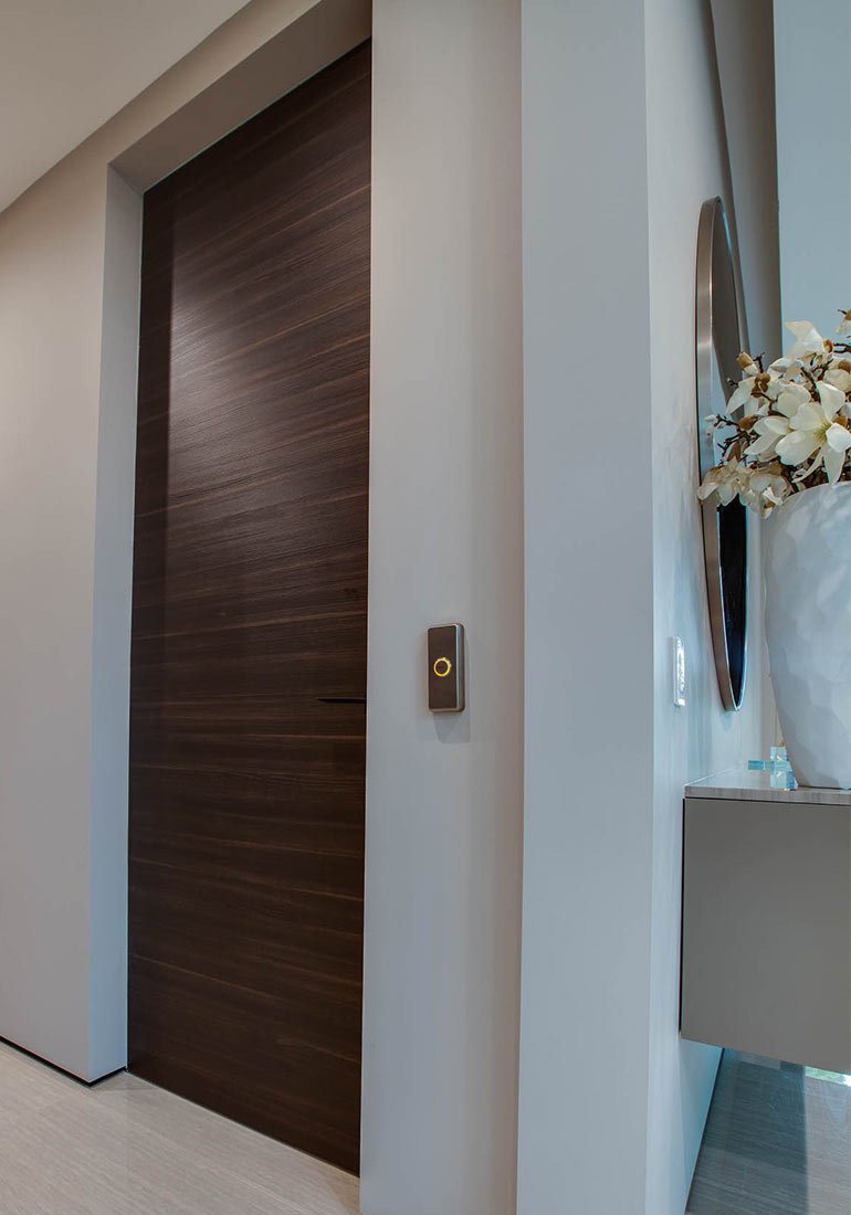 Closed wood-paneled elevator door with a call button on the wall