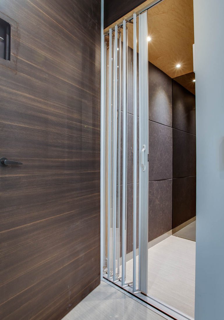 Open elevator gate beside a dark wood wall