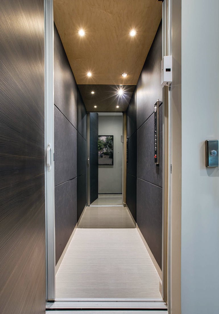 Modern elevator interior with dark walls and recessed ceiling lights