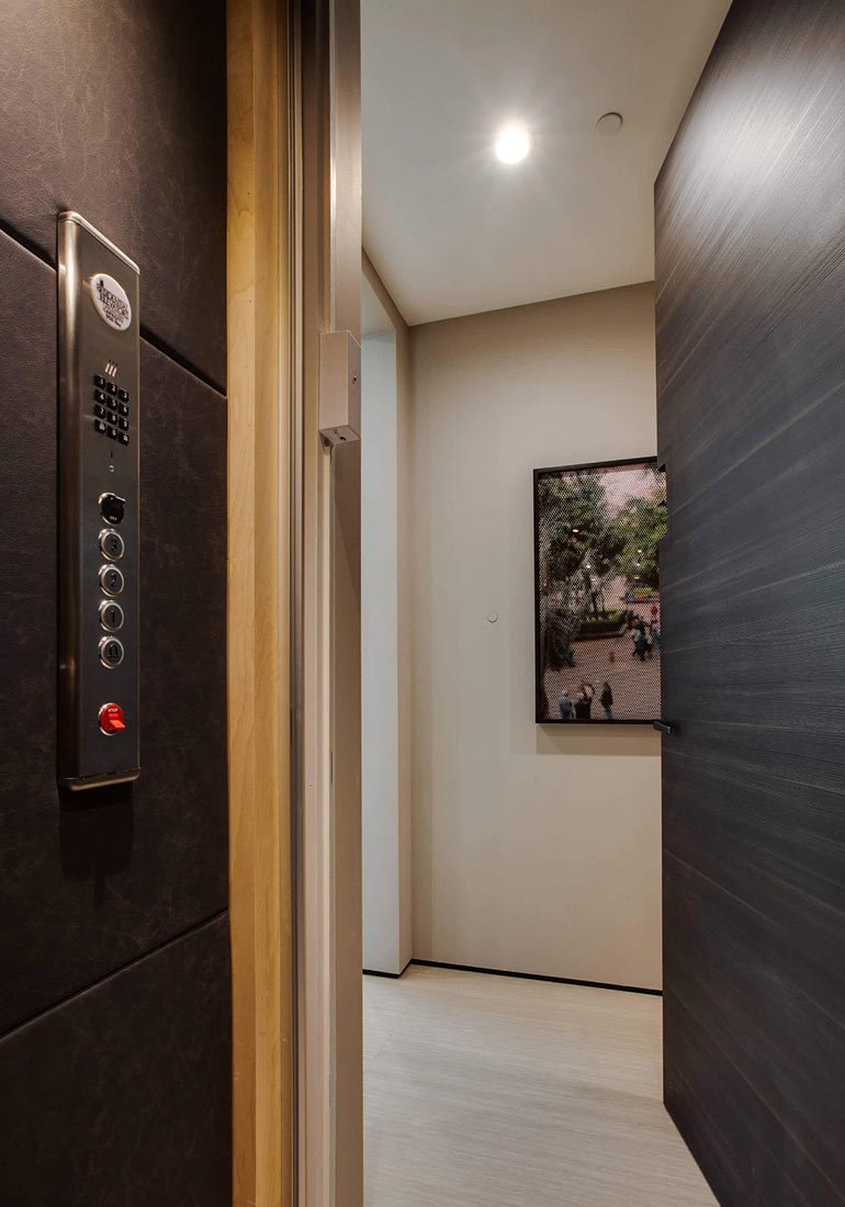 Elevator doorway with control panel visible beside a hallway