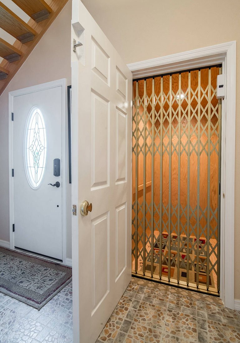 Home elevator with gold accordion gate next to an entry door