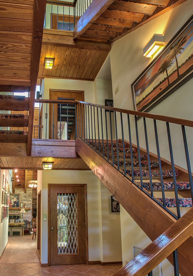 Wood-accented interior with multi-level stairs and an elevator with a metal accordion gate