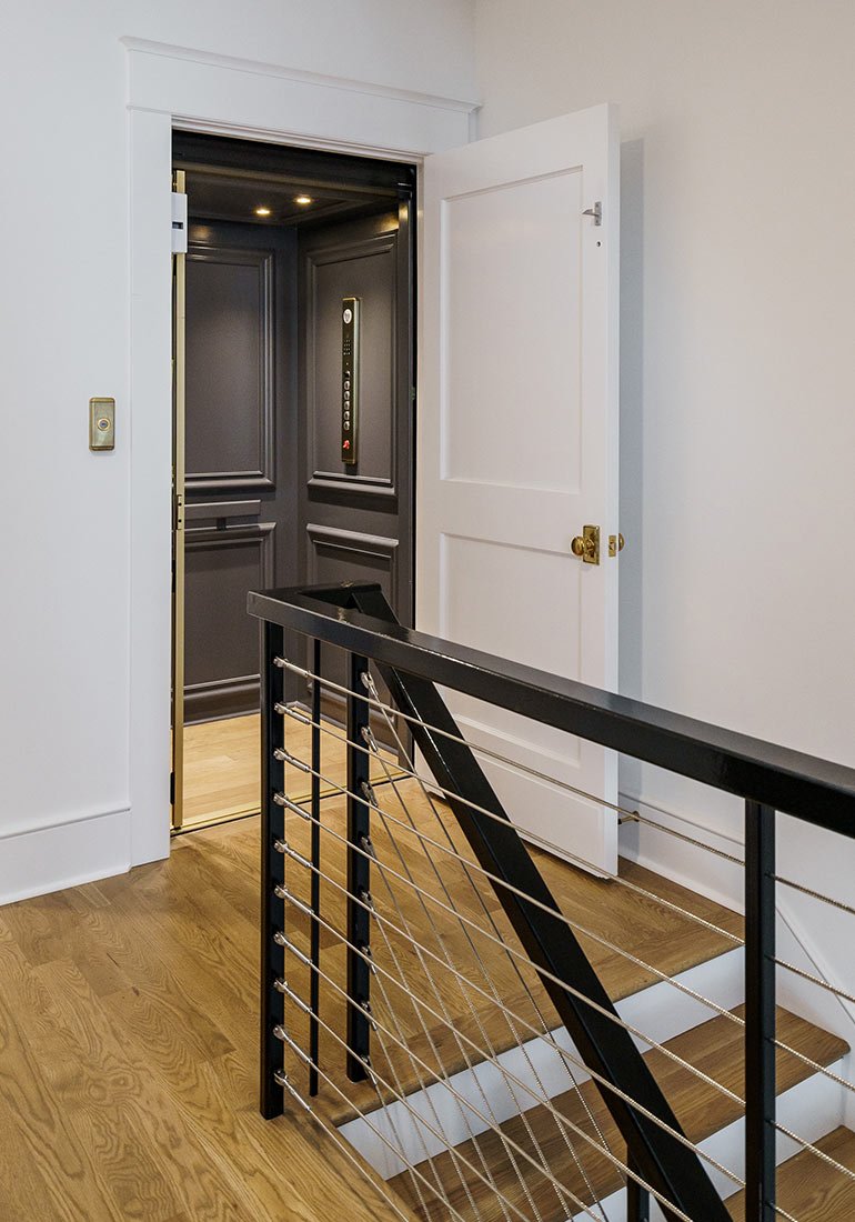 Home elevator with dark interior opening onto a landing with modern railing