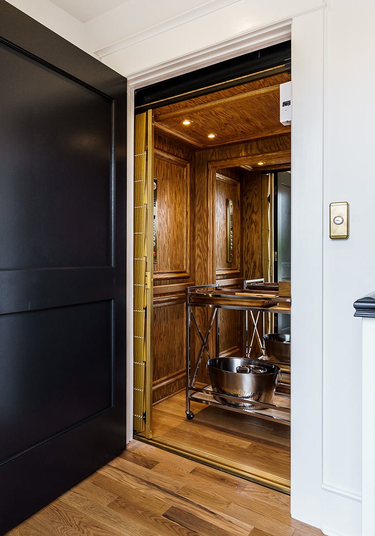 Wood-paneled home elevator with a serving cart inside